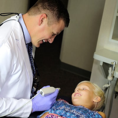 Dr. Vetter smiling while he works on a young female patient to illustrate that Fargo, ND offers many options for family fun including this dentist near you