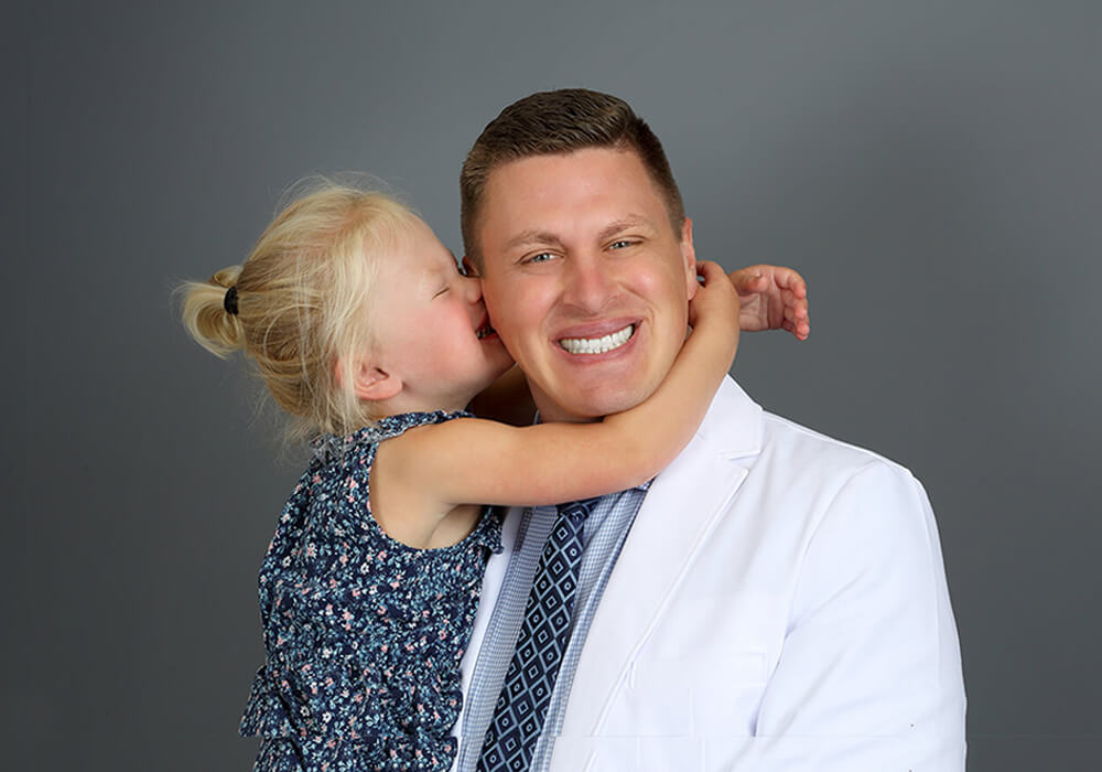 Dr. Vetter, a dentist in Fargo, ND, being hugged by his daughter