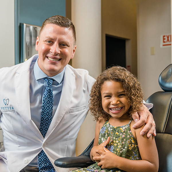 Dr. Vetter and his dental assistant smiling with a young girl in the dentist chair
